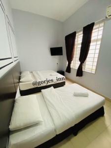 two beds in a small room with two windows at Gorjes Inn KLIA & KLIA2 in Sepang
