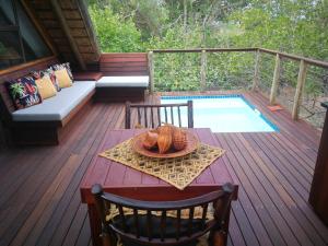 a table and chairs on a deck with a pool at Kruger River Villas- Treetop Loft in Marloth Park