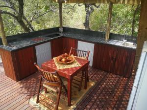 a table and chairs on a deck with a sink at Kruger River Villas- Treetop Loft in Marloth Park