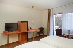 Habitación de hotel con cama, mesa y TV. en Micador Appartementhaus en Niedernhausen