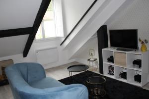 uma sala de estar com uma cadeira azul e uma televisão em PYRENE HOLIDAYS 4 étoiles spacieux dans immeuble atypique proche des thermes et des Pyrénées em Capvern