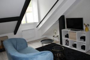 a living room with a blue chair and a television at PYRENE HOLIDAYS 4 étoiles spacieux dans immeuble atypique proche des thermes et des Pyrénées in Capvern