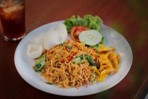a plate of food with noodles and vegetables on a table at Bingin Lodge Uluwatu in Uluwatu