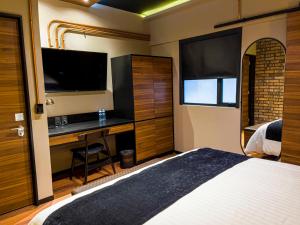 a bedroom with a bed and a desk with a television at Cadillac Hotel Boutique in Mexico City
