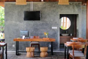 a dining room with a table and chairs and a tv at Bingin Lodge Uluwatu in Uluwatu