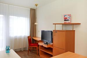 a room with a television and a desk with a chair at Sunday Hotel Wiesbaden Niedernhausen Apartments in Niedernhausen +38 photos