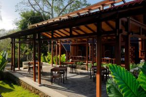 a wooden pavilion with tables and chairs in a garden at Bingin Lodge Uluwatu in Uluwatu