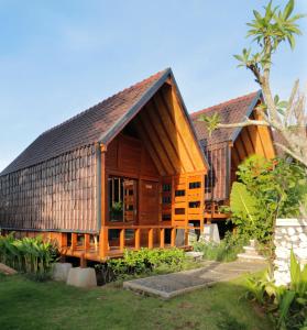 a wooden house with a gambrel roof at Bingin Lodge Uluwatu in Uluwatu