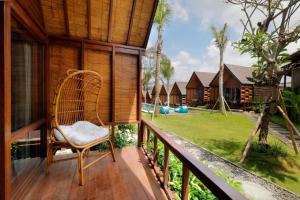 a wicker chair sitting on a balcony with a yard at Bingin Lodge Uluwatu in Uluwatu