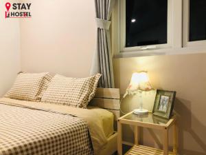 ein Schlafzimmer mit einem Bett und einem Tisch mit einer Lampe in der Unterkunft STAY hostel 2 - 350m from the ferry in Rạch Giá