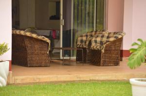 2 sillas de mimbre y una mesa en el patio en The Crown Inn Guest House, en Harare