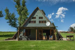 una casa con tetto di paglia su un campo di Penwarn Farm Lodge a Drakensberg Garden