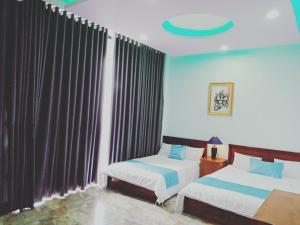 a bedroom with two beds and a window with curtains at Khách sạn Nghinh Phong Beach Tuy Hòa in Tuy Hoa