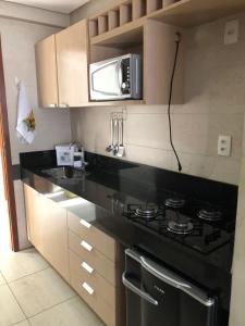 uma cozinha com um fogão e um micro-ondas em Flat à beira mar em João Pessoa