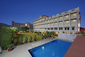 ein Hotel mit einem Schwimmbad vor einem Gebäude in der Unterkunft Mystical Valley View Resort and Spa, Udaipur in Udaipur