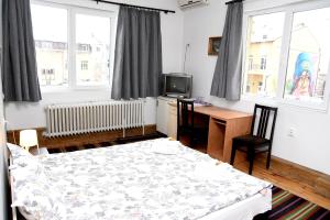 a bedroom with a bed and a desk and windows at Santa Sofia in Sofia