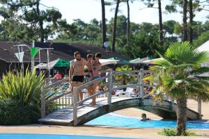 a group of people standing on a bridge over a pool at Camping Campéole Médoc-Plage - Maeva in Vendays-Montalivet