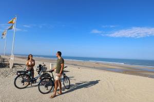two people standing on the beach with their bikes at Camping Campéole Médoc-Plage - Maeva in Vendays-Montalivet
