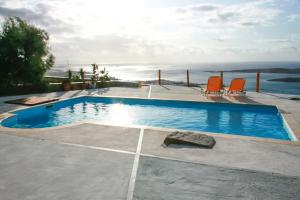 een zwembad met 2 stoelen en uitzicht op de oceaan bij 3 bedrooms villa with sea view shared pool and wifi at Paros 1 km away from the beach in Parikia