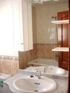 un bagno con un lavandino, una vasca e uno specchio di Charming House in Aldea Real with terrace and fireplace a Aldea Real