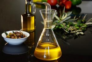 una botella de aceite de oliva junto a un tazón de aceitunas en Comfortable Apartment in Fabriano, 35 m² with Shared Pool, en Fabriano