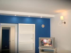a tv in a room with a blue wall at One bedroom appartement at Troia 200 m away from the beach with enclosed garden in Troia