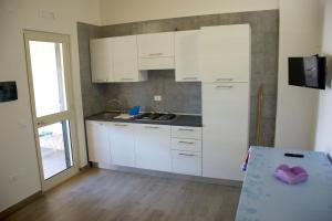 a kitchen with white cabinets and a table in it at One bedroom appartement at Vieste 700 m away from the beach with furnished garden in Vieste