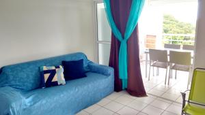 a blue couch in a living room with a window at Appartement moderne à Sainte-Anne 43 m² avec vue mer in Sainte-Anne