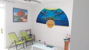 a room with three chairs and a table and paintings at Appartement moderne à Sainte-Anne 43 m² avec vue mer in Sainte-Anne