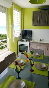 une cuisine avec des murs verts et une table avec deux chaises dans l'établissement Appartement d'une chambre avec vue sur la mer piscine partagee et balcon amenage a Sainte Anne a 1 km de la plage, à Sainte-Anne