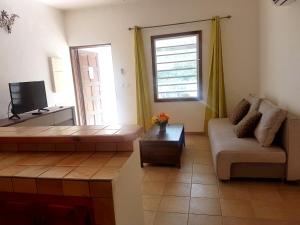 a living room with a couch and a tv at One bedroom appartement with furnished garden and wifi at La Savane 2 km away from the beach in Happy Bay