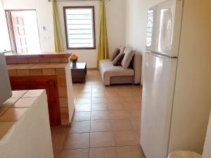 a kitchen with a refrigerator and a living room with a couch at One bedroom appartement with furnished garden and wifi at La Savane 2 km away from the beach in Happy Bay