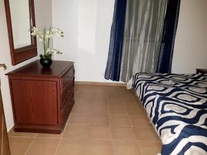 a bedroom with a bed and a dresser with flowers on it at One bedroom appartement with furnished garden and wifi at La Savane 2 km away from the beach in Happy Bay
