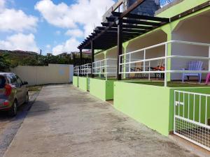 un edificio verde y blanco con un coche estacionado al lado en One bedroom apartement with furnished garden and wifi at La Savane 2 km away from the beach, en Happy Bay