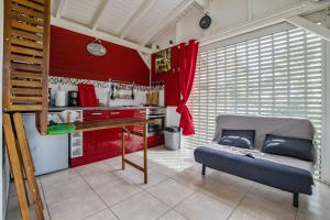 a kitchen with red walls and a bench in a room at Bungalow d'une chambre avec piscine partagee jardin clos et wifi a Petit Bourg in Petit-Bourg