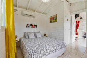 a bedroom with a bed in a white room at Bungalow d'une chambre avec piscine partagee jardin clos et wifi a Petit Bourg in Petit-Bourg