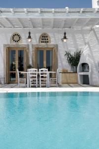 a house with a swimming pool with chairs and a table at Anthea Hotel in Tinos Town