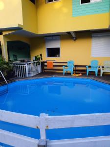 a large swimming pool with two chairs and a house at Bungalow de 2 chambres avec piscine partagee jacuzzi et terrasse amenagee a Le Gosier a 5 km de la plage in Le Gosier