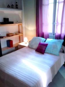 a bedroom with a white bed with purple and blue pillows at Appartement de 2 chambres avec jardin clos et wifi a Bocognano in Bocognano
