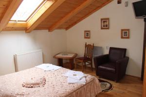 a bedroom with a bed and a chair and a window at Pensiunea Casa Alex in Sadova