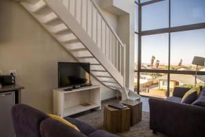 a living room with a tv and a staircase at Desert Sands Boutique B&B | Self-Catering in Swakopmund