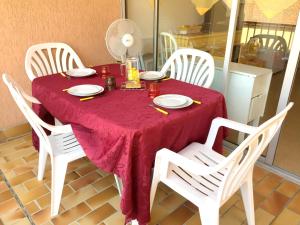 アルジェレス・シュル・メールにあるAppartement d'une chambre a Argeles sur Mer a 350 m de la plage avec piscine partagee et terrasse amenageeの赤いテーブルクロスと白い椅子付きのテーブル