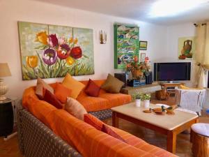 uma sala de estar com um sofá laranja e uma mesa em 6 bedrooms villa with sea view private pool and wifi at Loule em Loulé