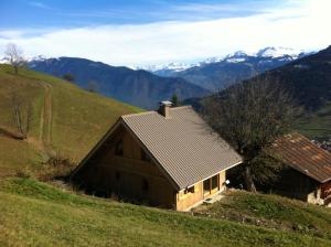 a barn on a hill with mountains in the background at Chalet de 4 chambres avec jardin amenage a Les Avanchers Valmorel a 7 km des pistes in Les Avanchers