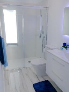 a white bathroom with a toilet and a sink at Modern apartment in Las Palmas 140 m² with air conditioning in Las Palmas de Gran Canaria