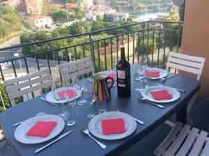 un tavolo blu con una bottiglia di vino e bicchieri di Appartement panoramique à Banyuls-sur-Mer, vue mer et montagne a Banyuls-sur-Mer
