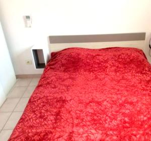 una camera da letto con una coperta rossa sul letto di Appartement panoramique à Banyuls-sur-Mer, vue mer et montagne a Banyuls-sur-Mer