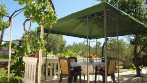 a table and chairs under a green umbrella at 2 bedrooms appartement at Slatine 250 m away from the beach with enclosed garden and wifi in Slatine