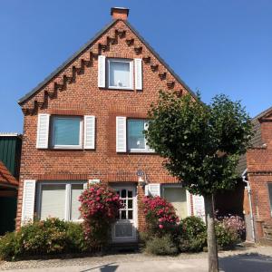 a red brick house with two windows and flowers at Möwenflug Apartments in Travemünde