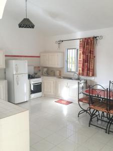 a kitchen with white appliances and a table in it at One bedroom appartement with sea view private pool and enclosed garden at Ouoran 1 km away from the beach in Ouoran